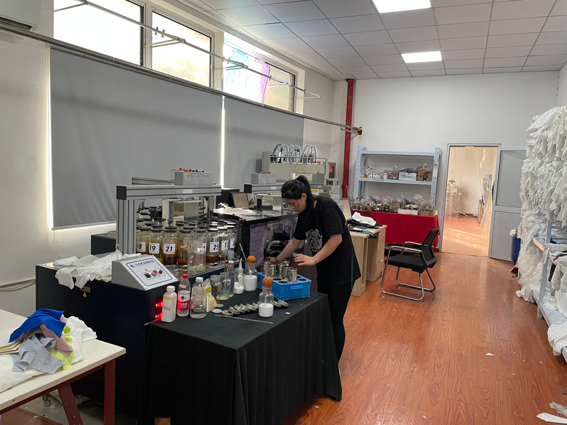 Technician at the RyderTex dye lab checking a colour recipe against dyed fabric swatches.