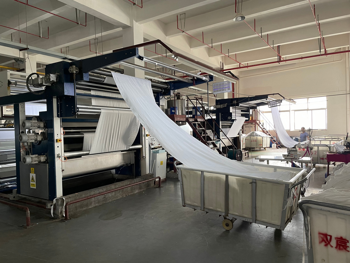 Stenter finishing machine at RyderTex with a loop of knitted fabric feeding through the frame.